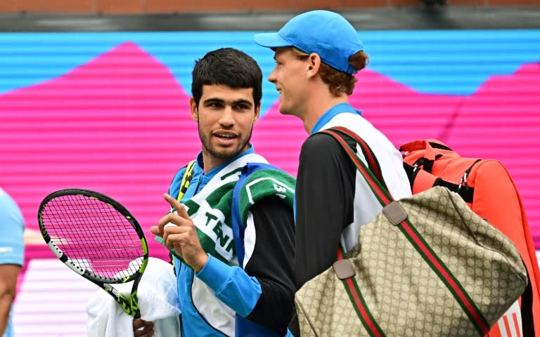 Carlos Alcaraz (izquierda) y Jannik Sinner (derecha) abandonan juntos la pista después de una interrupción por lluvia en el torneo de Indian Wells (Estados Unidos), el 16 de marzo de 2024 (Frederic J. BROWN)