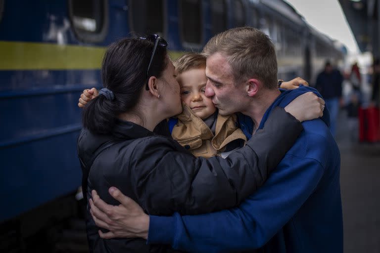 Oleksandr de 26 años, besa a su hijo Egor de 2 años y a su esposa Alyona de 26, al reunirse en la estación de tren después de más de dos meses separados por la guerra en Kiev, Ucrania, el 23 de abril de 2022