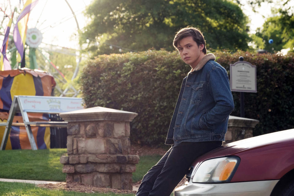 A boy sitting on car looking sideways