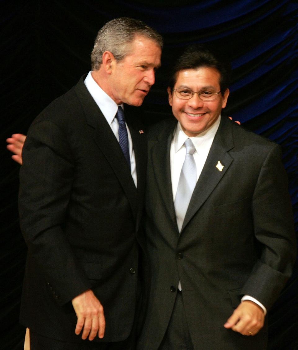 Then-President George W. Bush embraces U.S. Attorney General Alberto Gonzales as he walks offstage after the Hispanic Chamber of Commerce in April 2005 in Washington, D.C. Gonzales has "fond feelings" about his service.