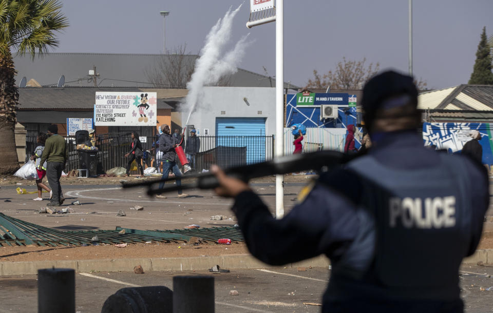 People throw stones at police as they attempt looting at Letsoho Shopping Centre in Katlehong, east of Johannesburg, South Africa, Monday, July 12, 2021. Police say six people are dead and more than 200 have been arrested amid escalating violence during rioting that broke out following the imprisonment of South Africa's former President Jacob Zuma. (AP Photo/Themba Hadebe)