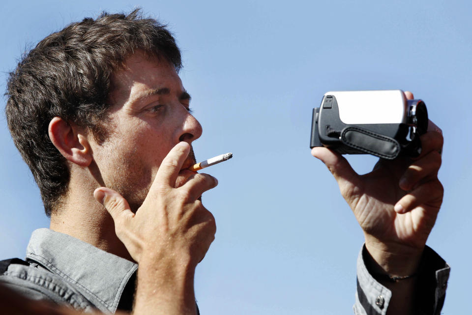 French Journalist Romeo Langlois smokes as he films after being released in San Isidro, southern Colombia, Wednesday, May 30, 2012. French journalist Romeo Langlois , who was taken by rebels on April 28 when they attacked troops he was accompanying on a cocaine-lab eradication mission, was handed over by the rebels to a delegation that included a French diplomat in San Isidro. (AP Photo/Fernando Vergara)