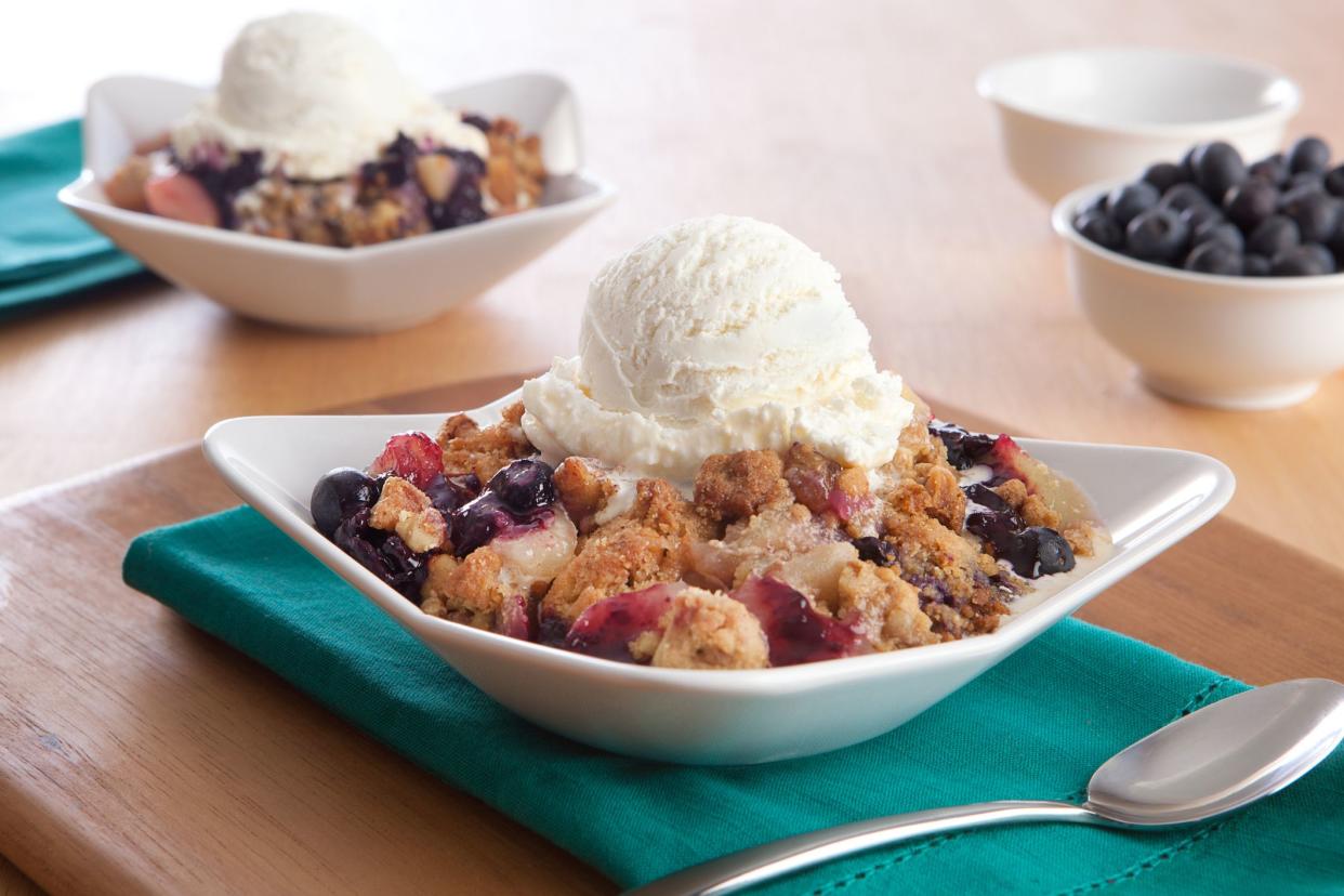 two blueberry cobblers with ice cream and extra blueberries