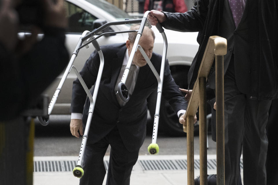 Harvey Weinstein walks up the steps at a Manhattan courthouse as an assistant carries his walker as he arrives for jury selection in his rape trial, Monday, Jan. 13, 2020, in New York. (AP Photo/Mark Lennihan)