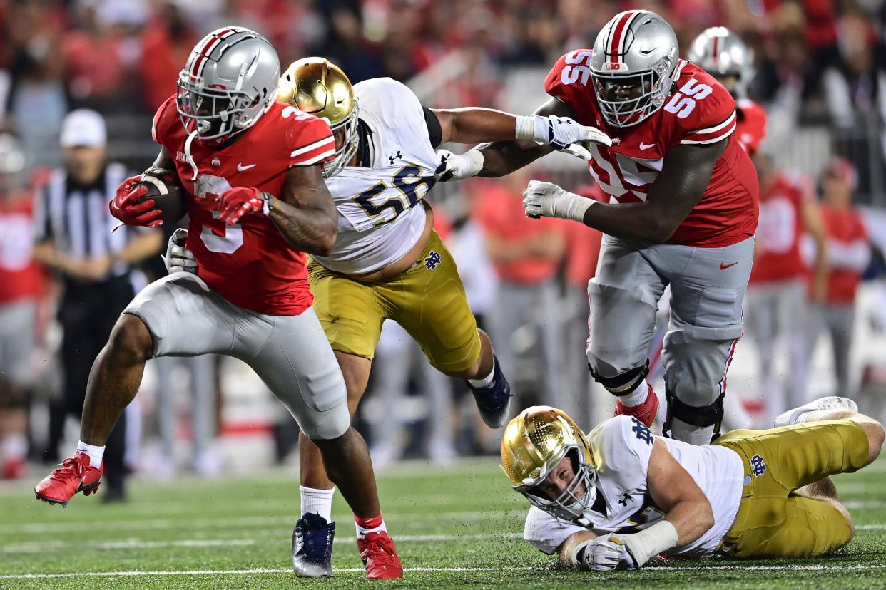 Ohio State running back Miyan Williams, left, runs the ball away from Notre Dame defensive lineman Howard Cross III, second from left, and linebacker JD Bertrand, bottom, during the fourth quarter of an NCAA college football game Saturday, Sept. 3, 2022, in Columbus, Ohio. (AP Photo/David Dermer)