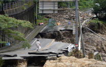 A man walks on heavily damaged road following a heavy rain in Kumamura, Kumamoto prefecture, southern Japan Monday, July 6, 2020. Rescue operations continued and rain threatened wider areas of the main island of Kyushu. (Koji Harada/Kyodo News via AP)