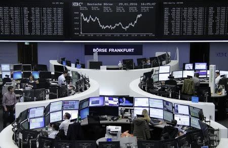 Traders work at their desks in front of the German share price index, DAX board, at the stock exchange in Frankfurt, Germany, January 29, 2016. REUTERS/Staff