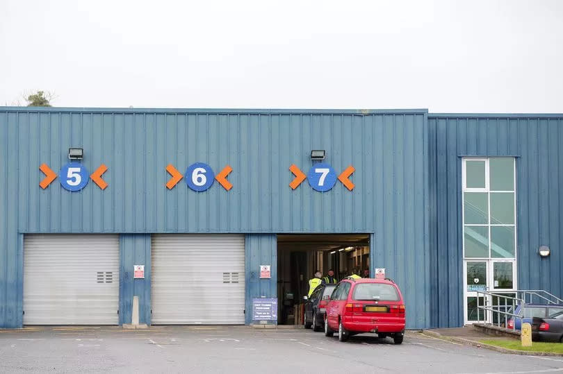 Stock image of an MOT centre, this one in Newtownards with a red and a black car queuing to get in via the right hand gate out of three