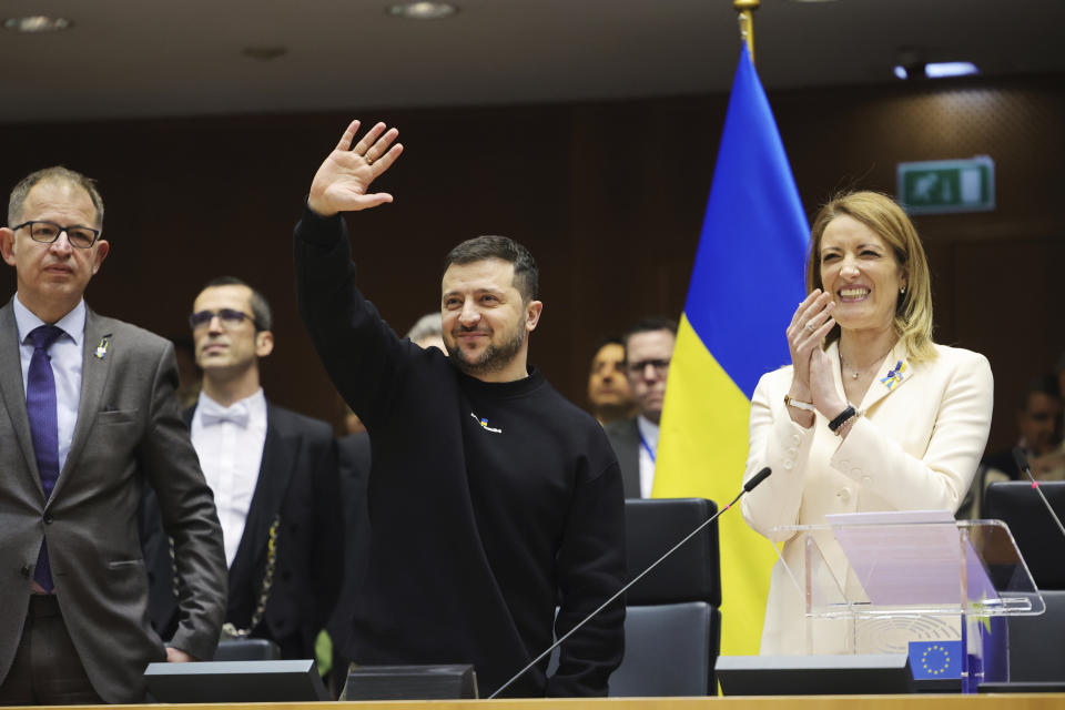 El presidente de Ucrania, Volodymyr Zelenskyy (centro), gesticula mientras la presidenta del Parlamento Europeo, Roberta Metsola (derecha), aplaude durante una sesión de la Eurocámara, en Bruselas Bélgica, el 9 de febrero de 2023. (AP Foto/Olivier Matthys)