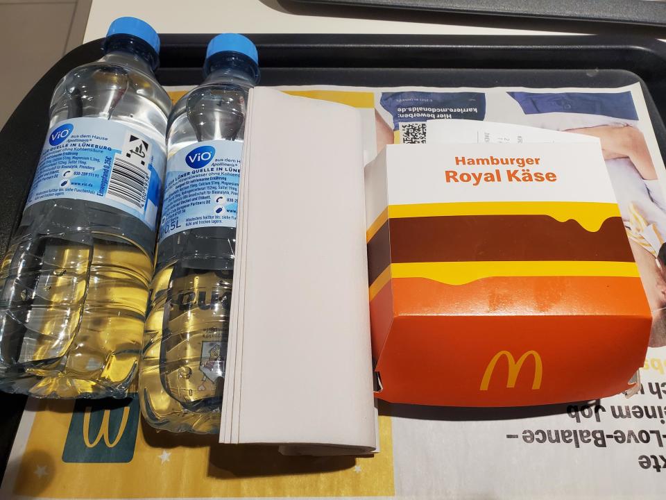 A McDonald's Hamburger Royal Käse container next to several bottles of water