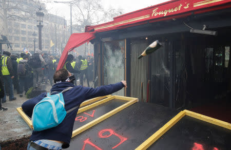 A protester throws a bottle during a demonstration by the "yellow vests" movement in Paris, France, March 16, 2019. REUTERS/Philippe Wojazer