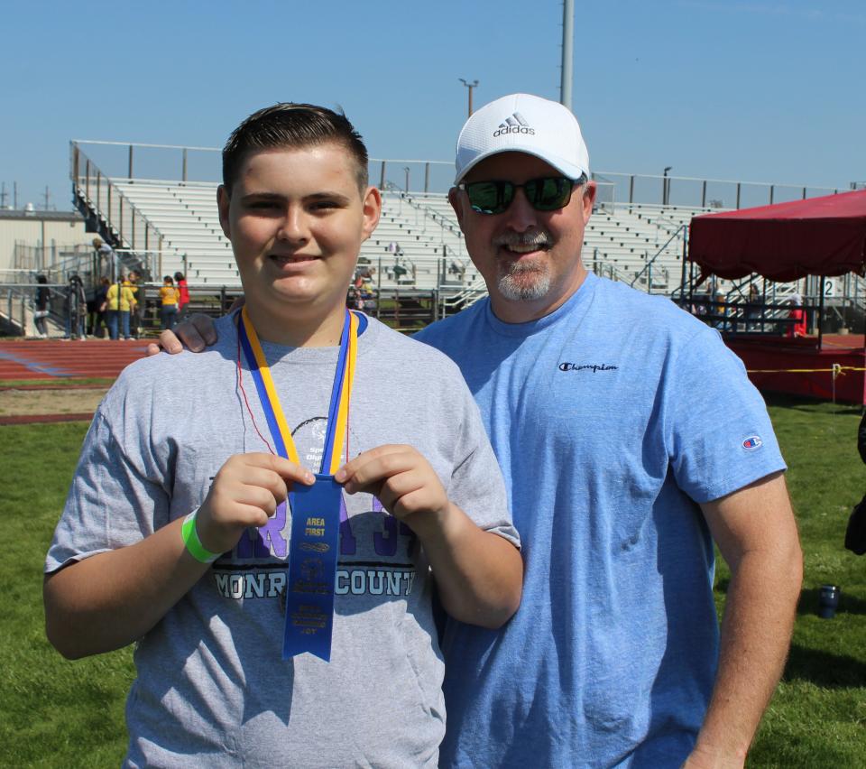 Kasee Clawson, 13, and his father, Jerad Clawson, celebrate Kasee's blue ribbon in the men’s softball throw event at this year's Monroe County Special Olympics.