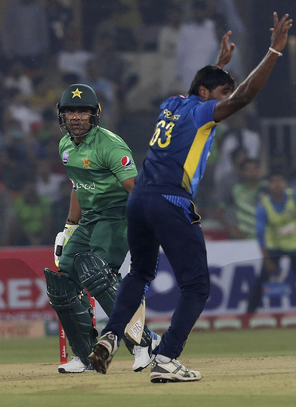 Pakistani batsman Umar Akmal, left, looks to umpire while Sri Lankan pacer Nuwan Pradeep appeals for his dismissal during first Twenty20 match at Gaddafi stadium in Lahore, Pakistan, Saturday, Oct. 5, 2019. (AP Photo/K.M. Chaudary)