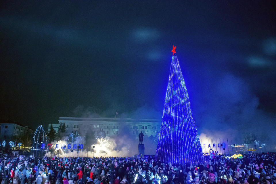 People gather at the Christmas tree decorated for Christmas and the New Year festivities in Luhansk, the capital of Russian-controlled Luhansk region, eastern Ukraine, Friday, Dec. 23, 2022. (AP Photo)