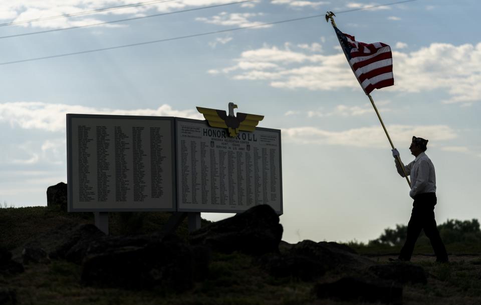 A member of the American Legion Post #41 honor guard carries an American flag towards the recreated honor roll near the entrance of the camp during a closing ceremony for the Minidoka Pilgrimage at the Minidoka National Historic Site, Sunday, July 9, 2023, in Jerome, Idaho. The honor roll is a 2011 replica of the original honor roll, built in 1943 by Minidoka incarcerees Kenjiro Nomura and Kamekichi Tokita to honor those from camp who served in the military. (AP Photo/Lindsey Wasson)