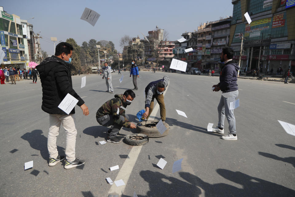 Nepalese demonstrators burn a tire and throw pamphlets during a general strike in Kathmandu, Nepal, Thursday, Feb. 4, 2021. A general strike called by a splinter faction of the ruling Communist party paralyzed life in Nepal on Thursday, shutting down schools, transportation and markets. Highways were deserted and shops were closed by the strike protesting Prime Minister Khadga Prasad Oli's decision to dissolve Parliament and call new elections. (AP Photo/Niranjan Shrestha)