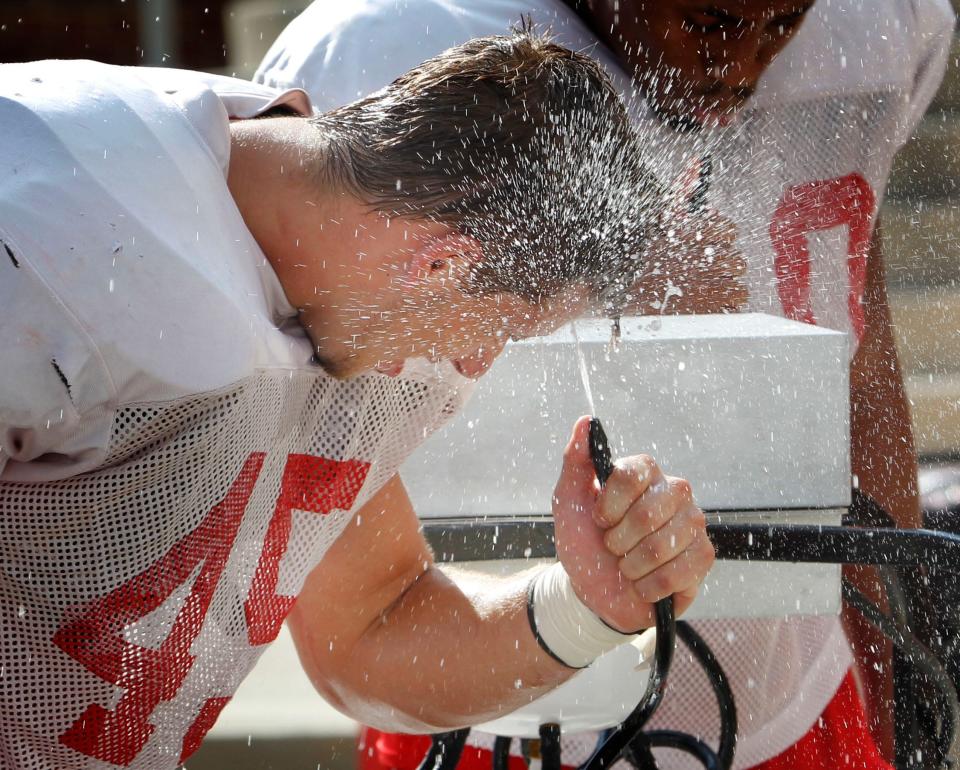 Austin Peay Junior linebacker Adam Noble sprays himself with water as he tries to stay cool during Thursday's practice at Governors Stadium.