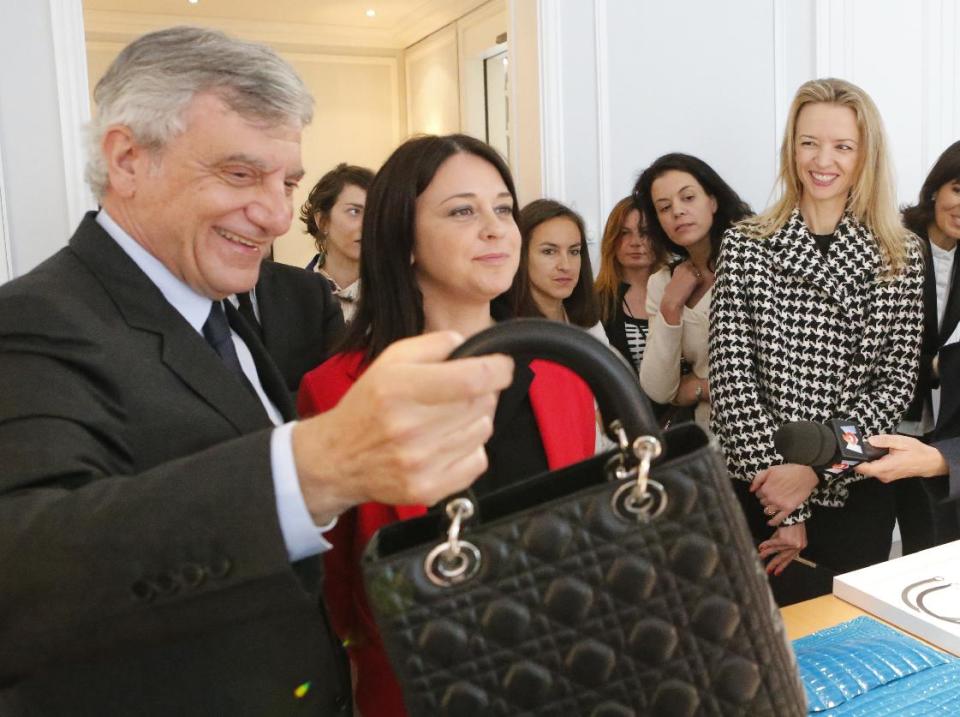 Dior President and Chief Executive Officer Sidney Toledano, left, holds a luxury bag Dior with Trade and Tourism deputy Minister Sylvia Pinel , center, and Assistant general manager Christian Dior Couture Delphine Arnault reacts during a visit of "Particular operation days" in LVMH, the world's largest luxury company at the Fashion House Dior in Paris, Saturday June 15, 2013.(AP Photo/Jacques Brinon)