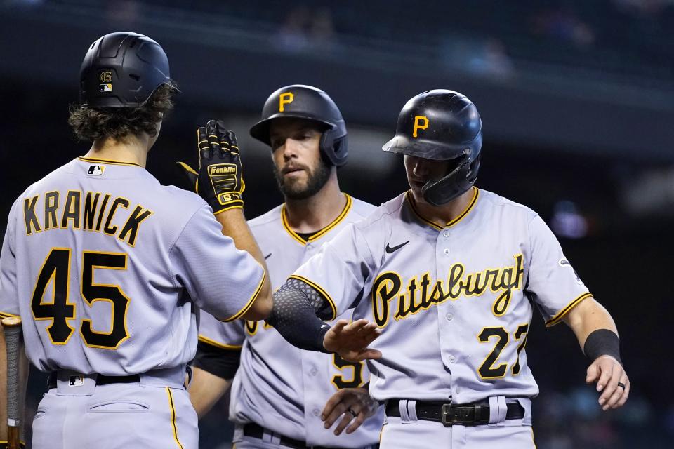 Pittsburgh Pirates' Kevin Newman (27) and Jacob Stallings, middle, are greeted by Max Kranick (45) after Newman and Stallings scored against the Arizona Diamondbacks during the fourth inning of a baseball game Wednesday, July 21, 2021, in Phoenix. (AP Photo/Ross D. Franklin)