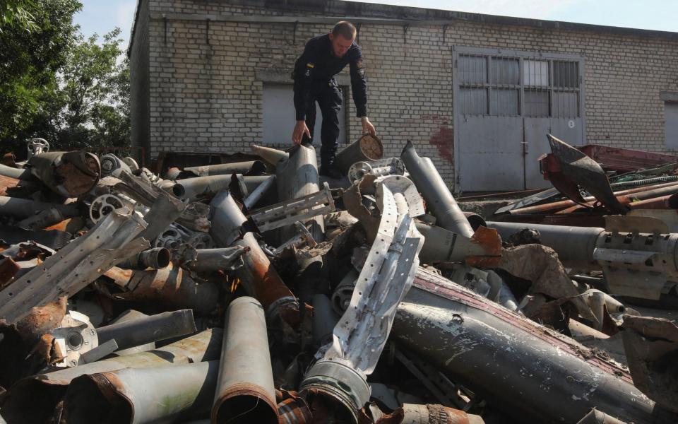 Ukrainian State Emergency Service workers stands atop of Russian missiles and rockets parts collected by his colleagues in Kharkiv - REUTERS