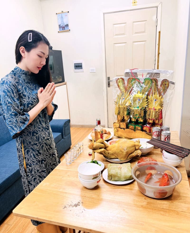 A bowl of goldfish is placed on a table next to prepared dishes and other food to worship the 