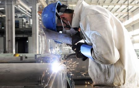 An employee welds the exterior of a vehicle along a production line at a factory in Qingdao, Shandong province December 1, 2014. REUTERS/China Daily