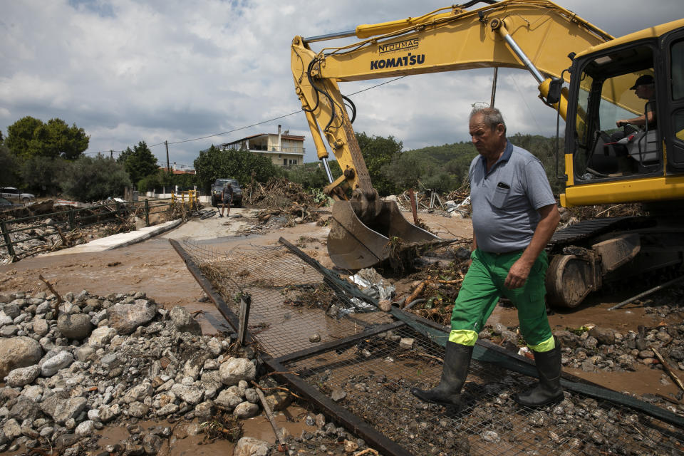 Workers move debris from a destroyed street following a storm at the village of Politika, on Evia island, northeast of Athens, on Sunday, Aug. 9, 2020. An elderly couple and an 8-month-old baby have been found dead and dozens have been trapped in their homes and cars from a storm that has hit the island of Evia, in central Greece, police say. (AP Photo/Yorgos Karahalis)