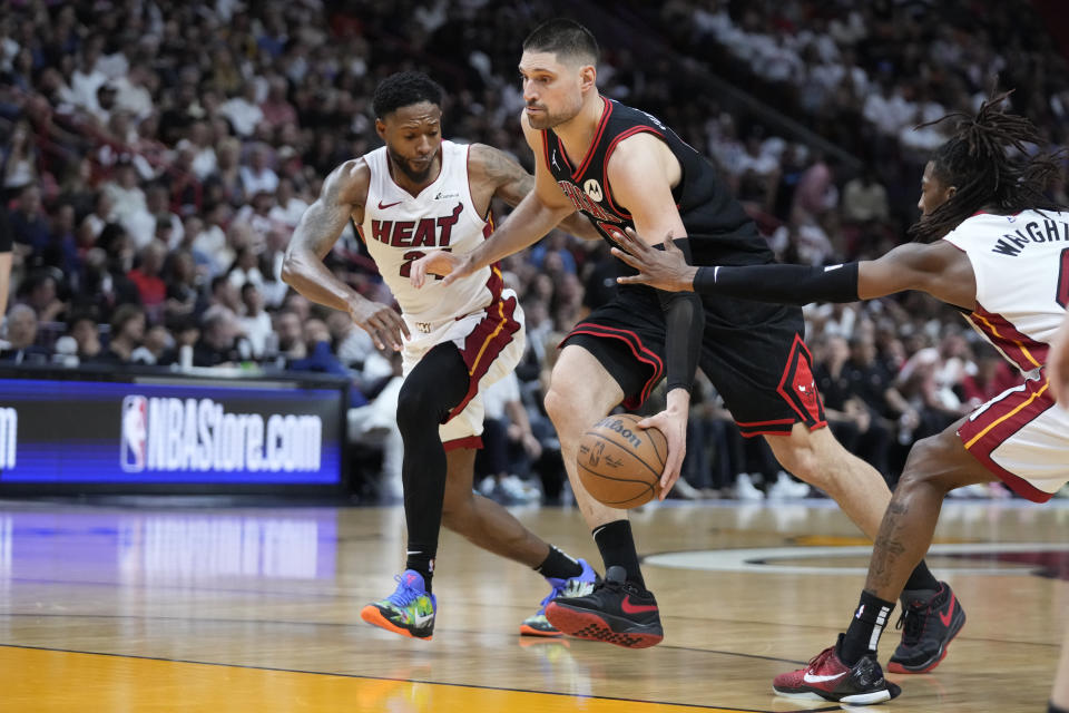 Chicago Bulls center Nikola Vucevic, center, drives to the basket against Miami Heat forward Haywood Highsmith, left, and guard Delon Wright during the second half of an NBA basketball play-in tournament game, Friday, April 19, 2024, in Miami. (AP Photo/Wilfredo Lee)