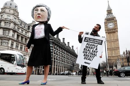 Anti-Brexit protesters, one wearing a giant Theresa May head, hold placards outside Parliament on the day the Prime Minister will announce that she has triggered the process by which Britain will leave the European Union, in London, March 29, 2017. REUTERS/Stefan Wermuth