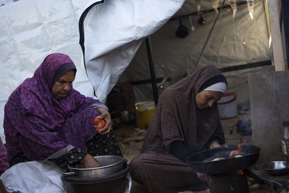 Randa Baker, a la derecha, que fue desplazada por el bombardeo israelí sobre la Franja de Gaza, prepara la comida de iftar con su madre en el primer día del mes sagrado islámico del Ramadán, el 11 de marzo de 2024. (AP Foto/Fatima Shbair)