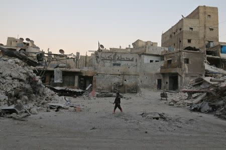 A boy walks amid damaged buildings in the rebel held area of al-Kalaseh neighbourhood of Aleppo, Syria, September 29, 2016. REUTERS/Abdalrhman Ismail