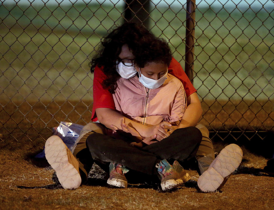 Immigrants detained by the US Border Patrol rest along the fence, Tuesday, May 17, 2022, in La Joya, Texas. (Joel Martinez/The Monitor via AP)