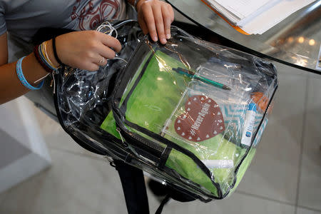 Daniela Menescal, who was injured by shrapnel during the mass shooting at Marjory Stoneman Douglas High School, looks for her belongings inside her clear backpack at her house in Parkland, Florida, U.S., April 4, 2018. REUTERS/Carlos Garcia Rawlins