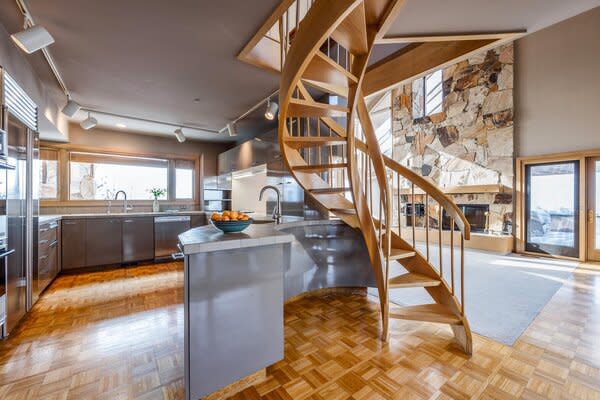 This custom spiral wood staircase comes from the mind of architect Fred Babcock. His redesign of this modern log cabin in Salt Lake City, Utah, contributes to the home’s bright interior without blocking any natural light. The stairs’ organic light-toned wood blends beautifully with the cabin’s interior colors, flooring, and stonework.