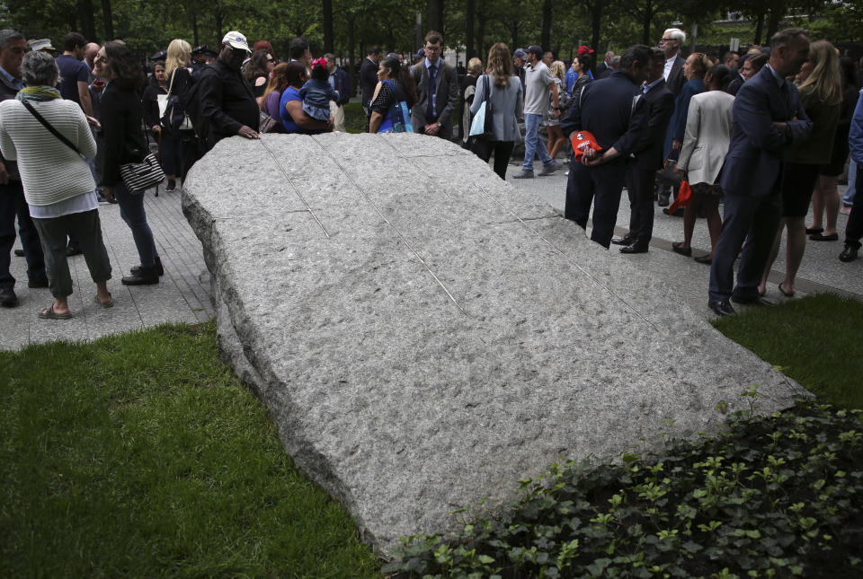 FILE- In this May 30, 2019 file photo, people gather around stones that are part of a new 9/11 Memorial Glade on the grounds of the National September Memorial and Museum after the Glade's dedication ceremony in New York. Set in a glade of trees during the spring 2019, the granite slabs recognize an initially unseen toll of the 2001 terror attacks: firefighters, police and others who died or fell ill after exposure to toxins unleashed in the wreckage. (AP Photo/Seth Wenig, File)