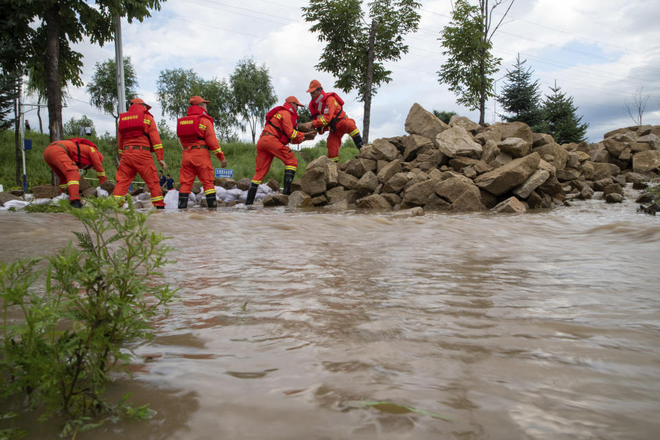 In this aerial photo released by Xinhua News Agency, firefighters use rocks to build a barrier against flood waters near Dawan Village of Dong'an District, Mudanjiang in northeastern China's Heilongjiang Province, Aug. 5, 2023. Rain continued to pelt northeastern China in the wake of Typhoon Doksuri as authorities reported more fatalities and missing people while evacuating thousands more. (Zhang Tao/Xinhua via AP)