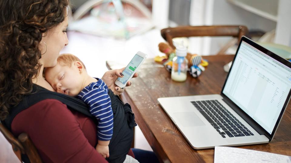 Cropped shot of a mother texting on her cellphone while looking after her baby boy at home.