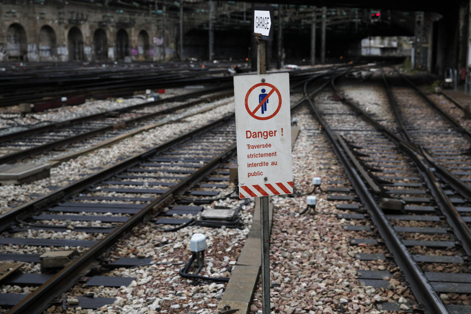 A security signs forbidden to cross the tracks at Gare de L'Est train station in Paris, Saturday, Dec. 7, 2019. French strikes are disrupting weekend travel around the country, as truckers blocked highways and most trains remained at a standstill because of worker anger at President Emmanuel Macron's policies as a mass movement against the government's plan to redesign the national retirement system entered a third day. (AP Photo/Francois Mori)