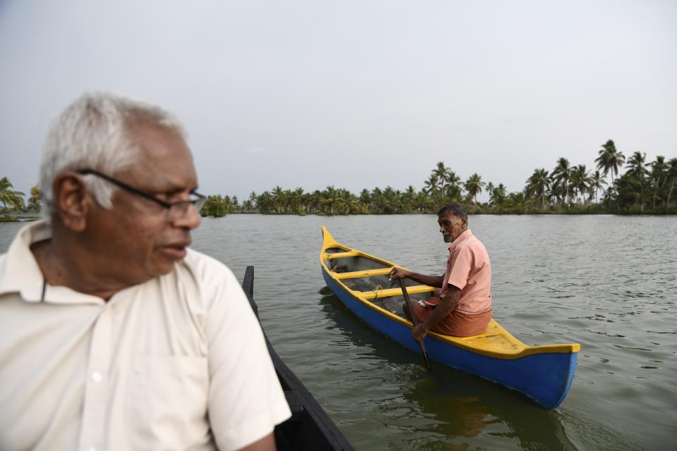 M.M. Chandu, 78, right, talks to his neighbor Francis Kalathungal while he moves toward his water surrounded farmland in Chellanam village, a suburb of Kochi, southern Kerala state, India, March 24, 2023. Chandu says he has been personally guarding his little over two acres of farmland every night for the past 22 years. (AP Photo/R S Iyer)