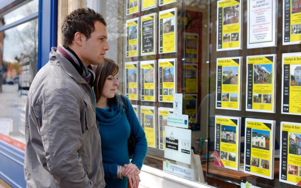 A young couple browse the listings in an estate agency window - Alamy Pay