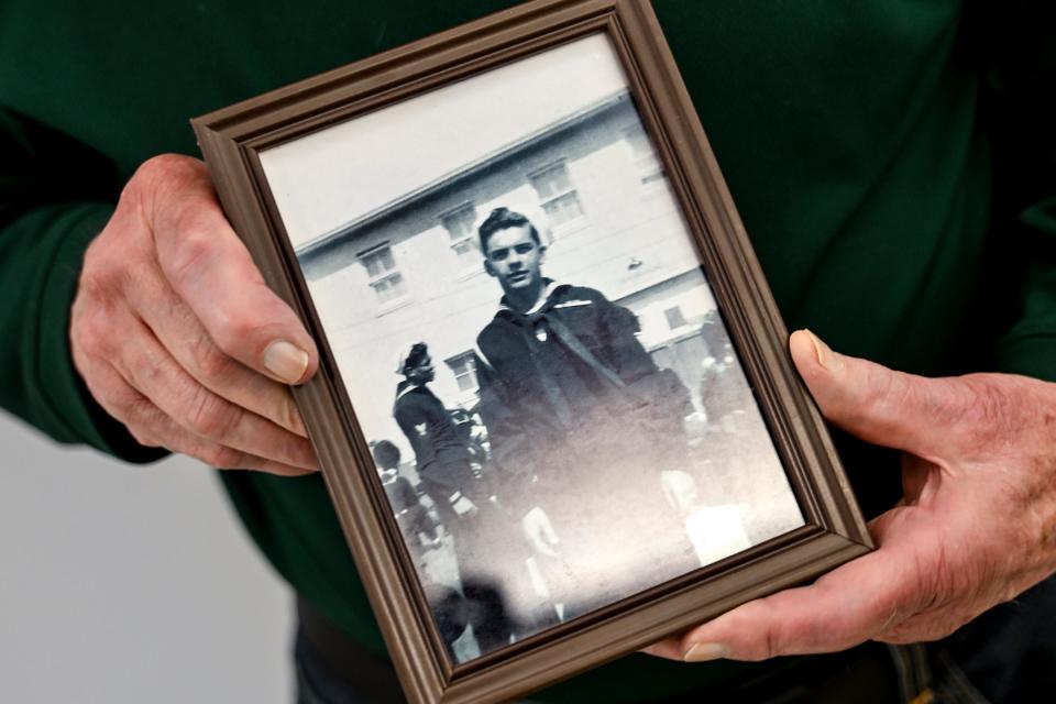Richard Masters holds a photograph of himself in the U.S. Navy around the time he served in World War II on Tuesday, April 30, 2024, near a display of other community members who served in the war at the Hannah Community Center in East Lansing.