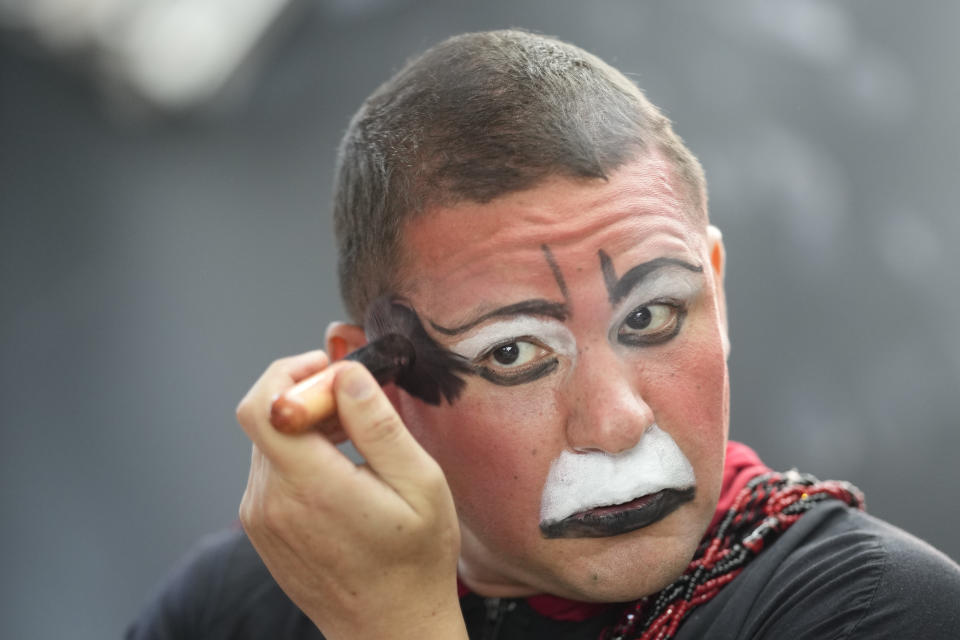 Psychiatrist Flavio Falcone, known as the clown doctor of Crackland, prepares to perform in downtown Sao Paulo, Brazil, Thursday, May 11, 2023. Once a week, Falcone dresses as a clown. He is joined by a team that performs an act in Crackland every week. They invite addicts to sing karaoke, enter a competition for a $10 prize or join the five-person jury. Participants are put in touch with health care professionals. (AP Photo/Andre Penner)