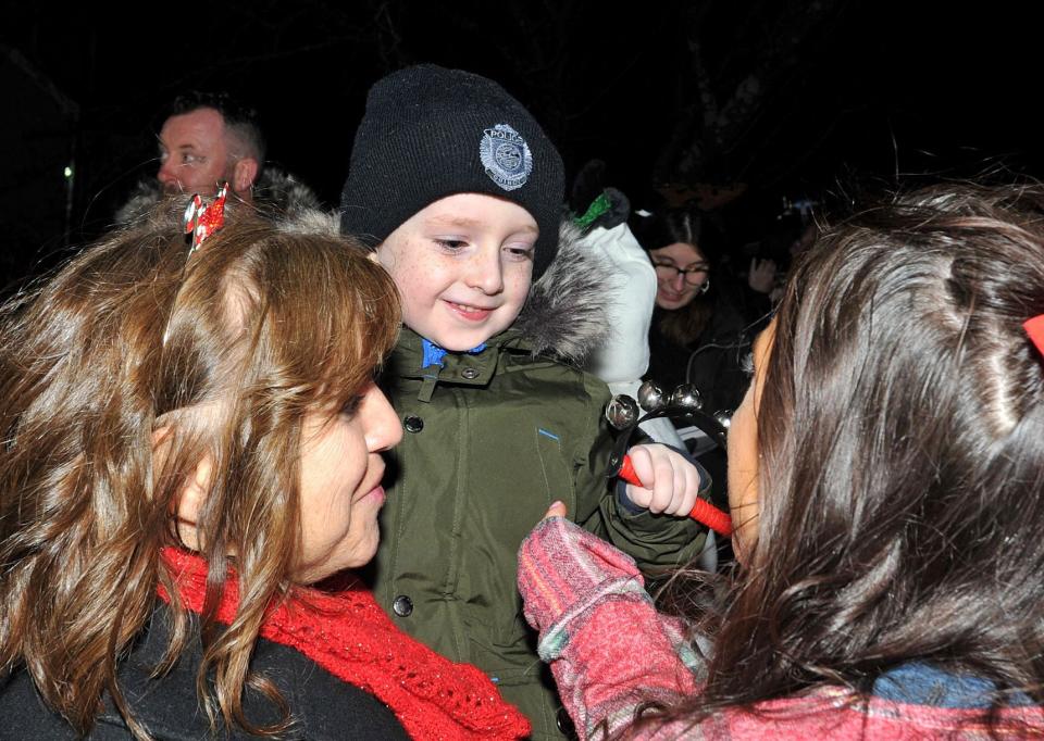 "The Mighty Quinn" Waters, 5, center, is all smiles as he greets Christmas carolers Rose Pope, left, and Loretta Pope, right, both of Braintree, outside his Weymouth home Sunday, Dec. 19, 2021.