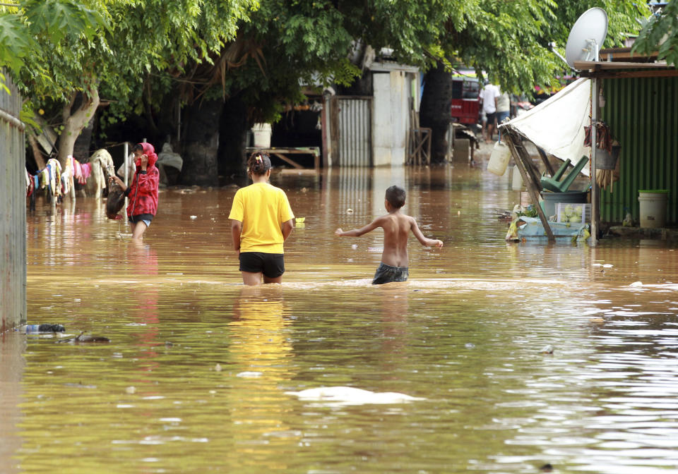 People wade through flood waters in Dili, East Timor, Monday, April 5, 2021. Multiple disasters caused by torrential rains in eastern Indonesia and neighboring East Timor have left dozens of people dead and missing and displaced thousands. (AP Photo/Kandhi Barnez)