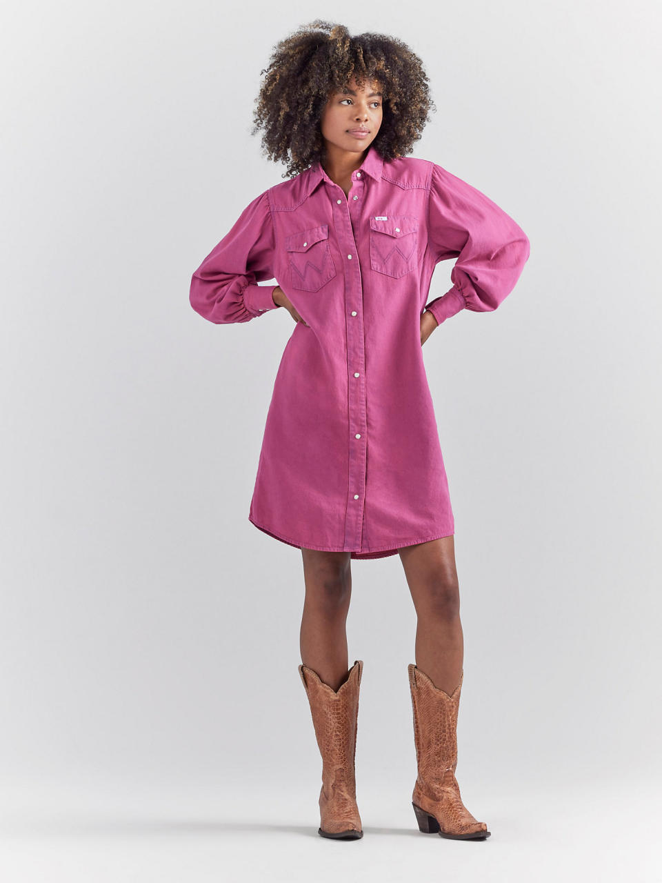 model wearing pink denim dress with brown cowboy boots