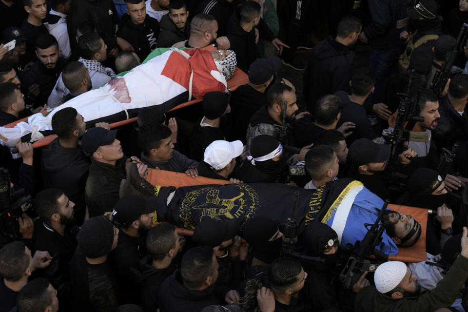 Palestinian mourners carry the bodies of school teacher Jawad Bawaqna, 57, left, and Adham Jabareen, 28, during their funeral in the in the West Bank city of Jenin, Thursday, Jan. 19, 2023. Palestinian officials and media reports say Israeli troops shot and killed the Palestinian schoolteacher and a militant during a military raid in the occupied West Bank. (AP Photo/Majdi Mohammed)