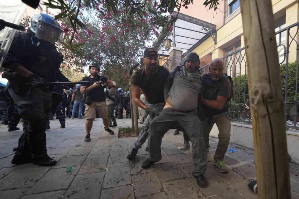 A demonstrator is blocked by plain clothes policemen during clashes broke out between demonstrators and Italian Policemen in riot gears on the occasion of a protest against the G20 Economy and Finance ministers and Central bank governors' meeting in Venice, Italy, Saturday, July 10, 2021. (AP Photo/Luca Bruno)