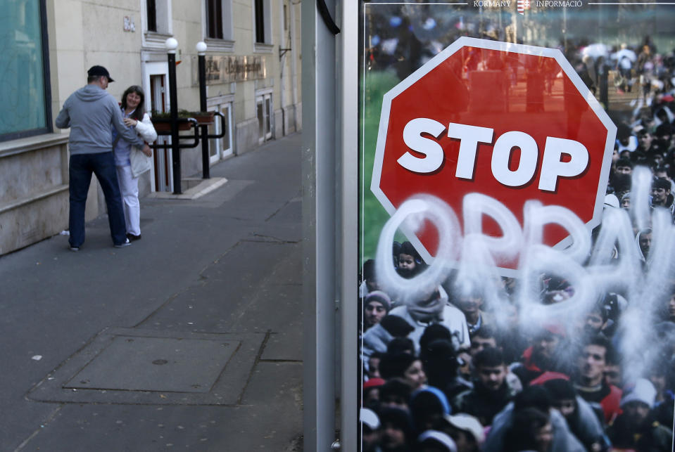 FILE - In this Monday, April 9, 2018, file photo, a man hugs a woman by an anti-migration billboard from the Hungarian government vandalized with paint reading: "Orban", in Budapest, Hungary. With a campaign centered on stopping immigration, Hungary’s ruling Fidesz party is expected to continue its dominance in the European Parliament election at the end of May. While Hungary has been practically closed to immigrants from the Middle East, Asia and Africa since Prime Minister Viktor Orban had border fences built in 2015, he continues to warn voters about the threat of a “migrant invasion” that would put at risk Europe’s Christian culture. (AP Photo/Darko Vojinovic, File)