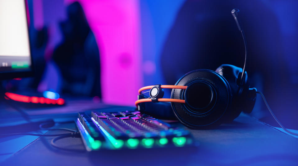 Professional headphones with microphone for video games and cyber sports gaming monitor in neon color blur background.