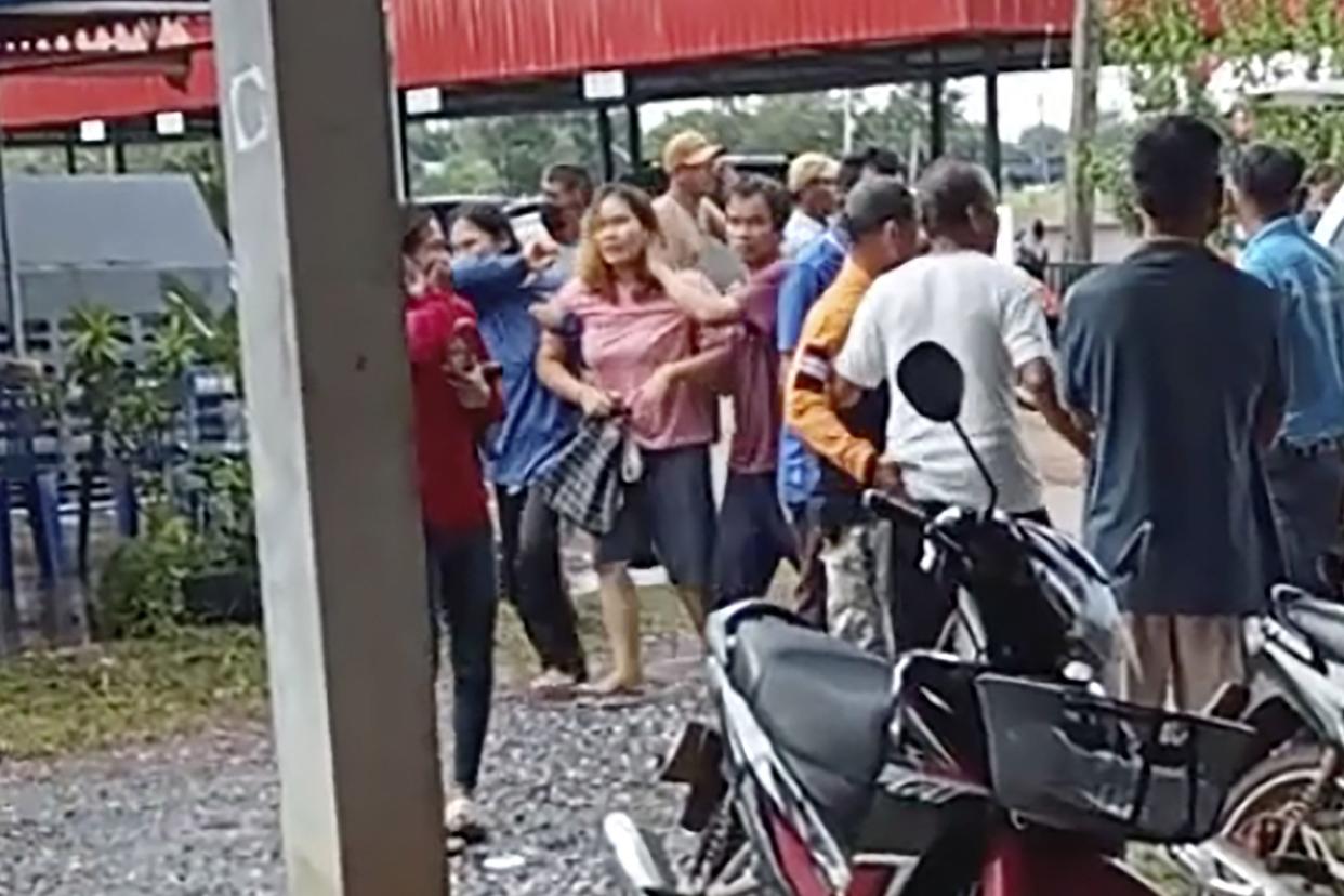 In this image taken from video, a distraught woman is led away from the site of an attack at a daycare center, Thursday, Oct. 6, 2022, in the town of Nongbua Lamphu, northeastern Thailand.